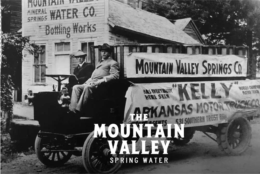 Black & white image of Mountain Valley Spring Water delivery truck outside the bottling works with logo