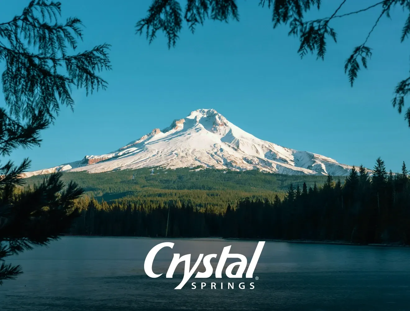 Snow covered mountain with water in the foreground and Crystal Springs logo