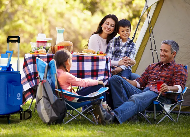 Family enjoying a meal while camping with a Primo portable water dispenser